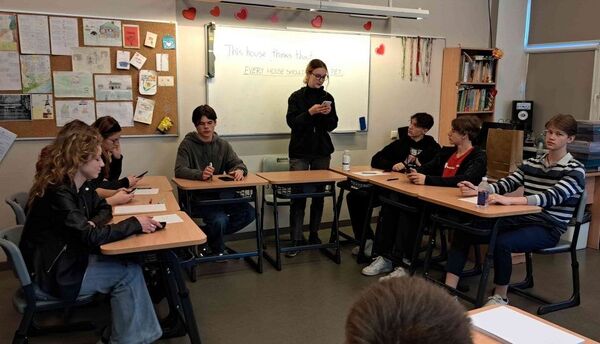 Pupils sitting at desks in a classroom and debating
